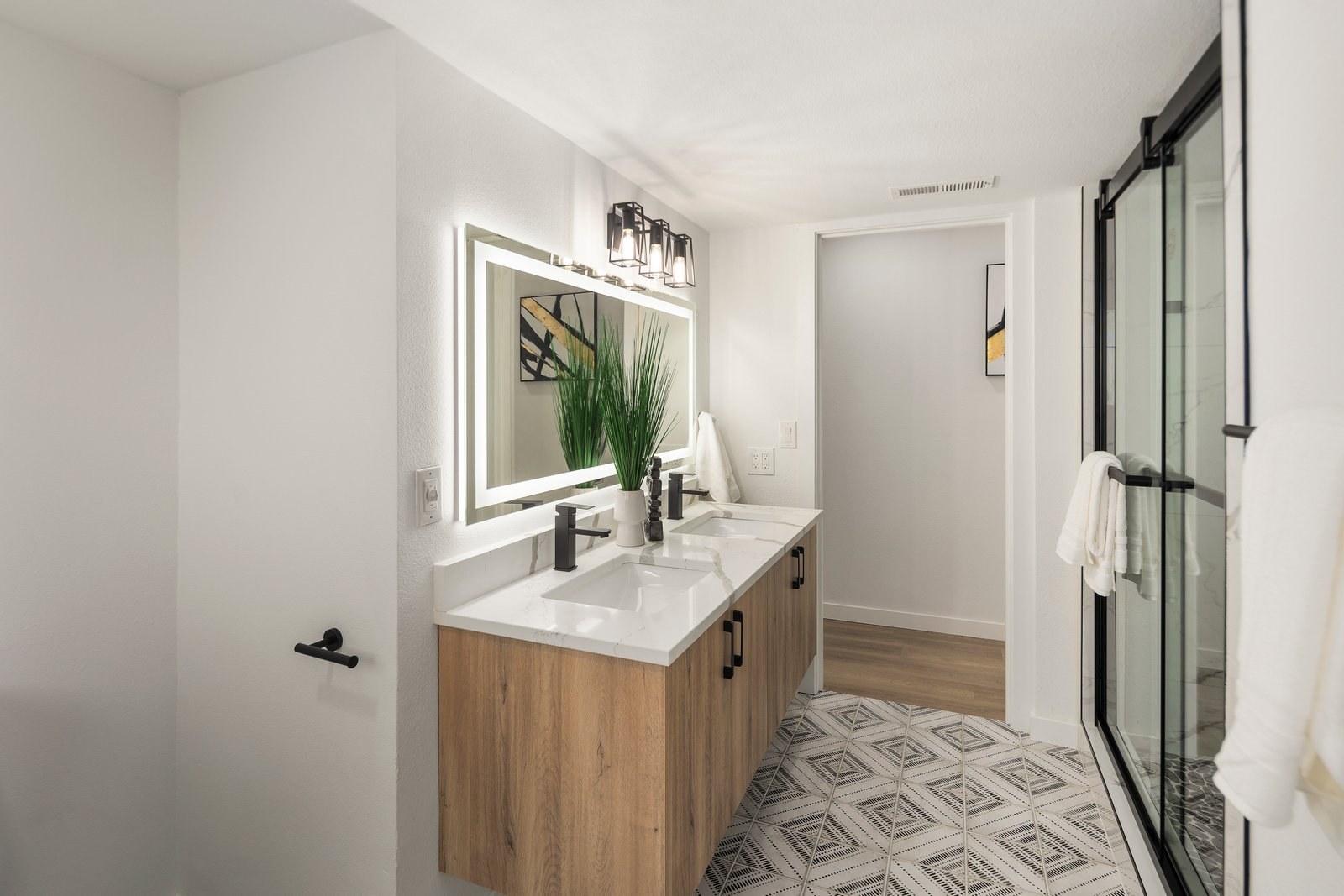 Bathroom vanity with lit mirror and glass shower