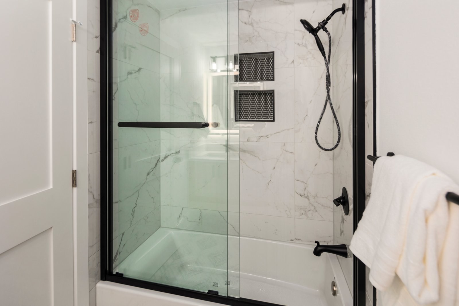 Marble tiled walk-in shower with black fixtures
